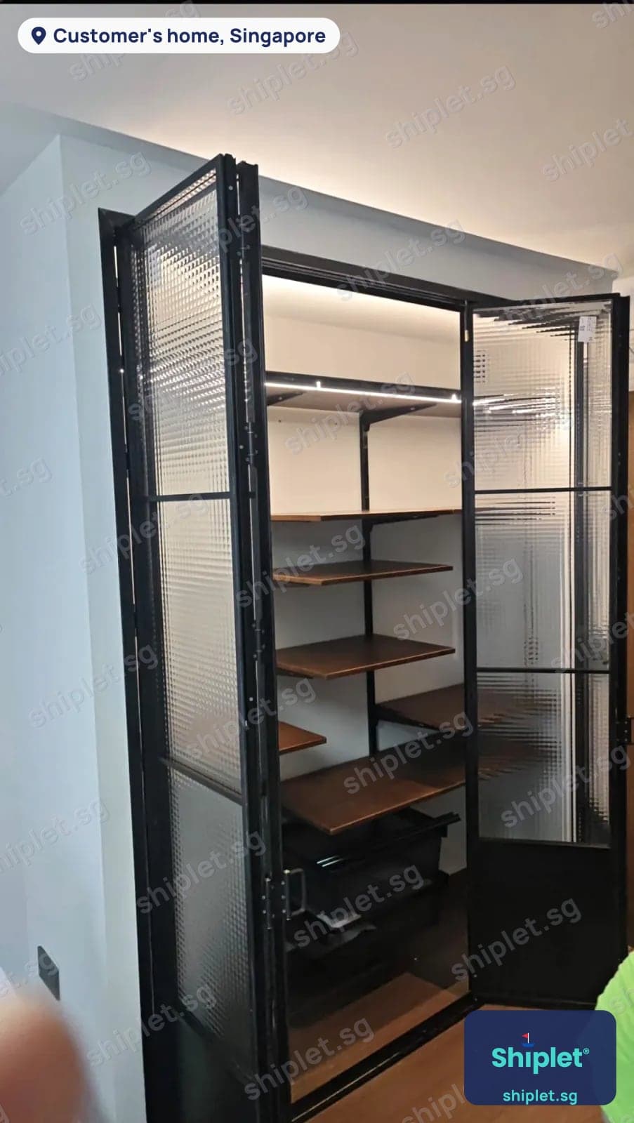 Walk-in wardrobe with black-framed fluted glass doors and wooden shelving installed in a Singapore flat
