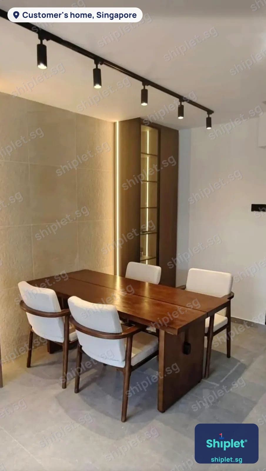 Solid wood dining table with four upholstered armchairs assembled in a dining room with a lit display shelf