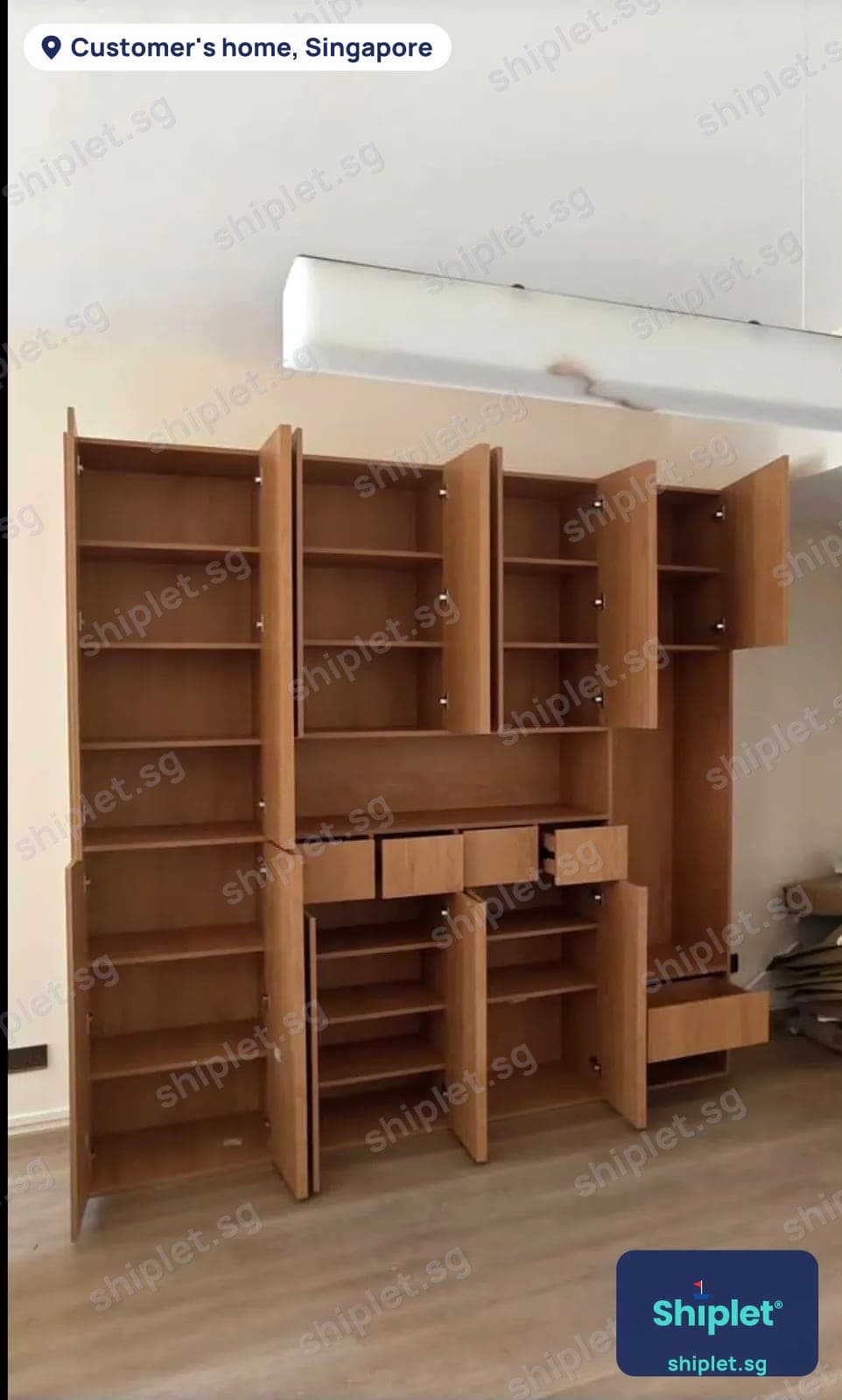 Wall-to-wall oak bookcase and cabinet with doors and drawers open after assembly